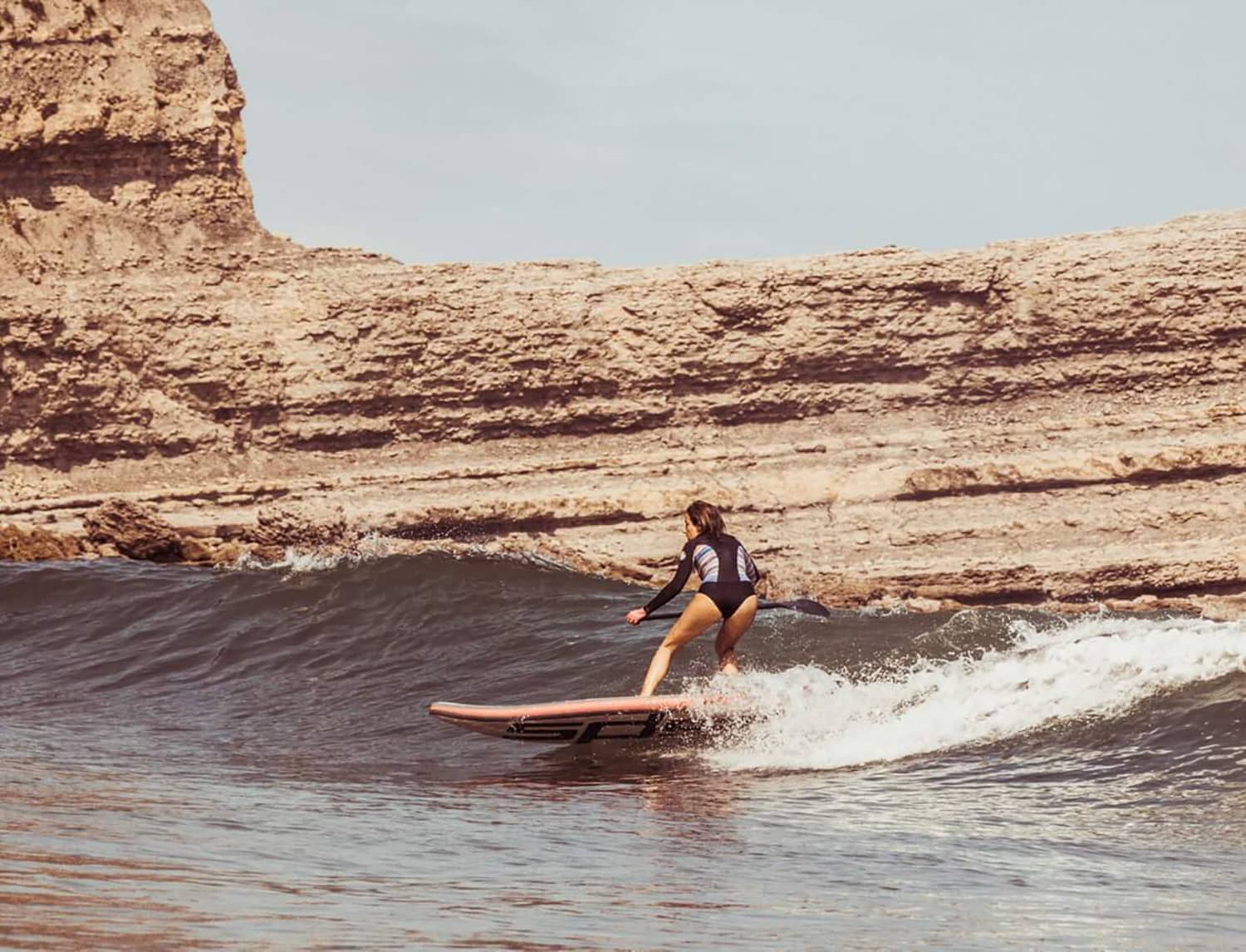 Surfista con tabla wave de SPS bajando una ola hacia la derecha